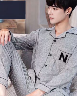 Men's gray cotton pajamas with white stripes worn by a man sitting on a sofa in a house