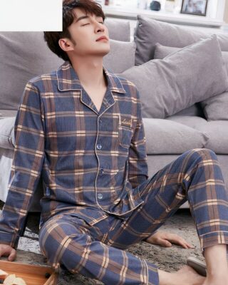 Trendy cotton checkered pajamas for men worn by a man sitting on a carpet in a house