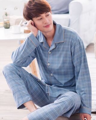 Very trendy light blue cotton pajamas for men worn by a man sitting on a carpet in a house