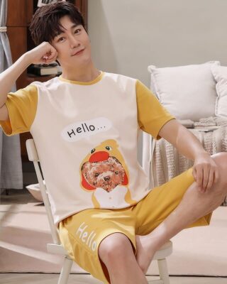 Summer pajamas t-shirt and cotton shorts with dog print worn by a man sitting on a chair in a house