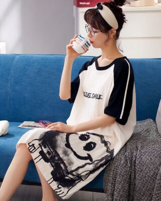 Short-sleeved cotton pajamas with please smile inscription worn by a woman sitting on a sofa in a house