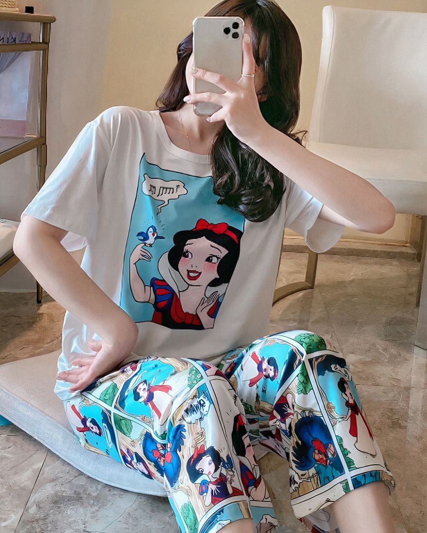 White two-piece pyjamas with Snow White pattern worn by a seated woman in white and blue