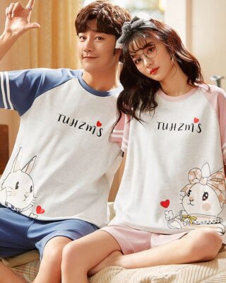 Two-piece pyjamas made of cotton t-shirt and shorts with a fashionable bear pattern, worn by a couple sitting on a bed in a house