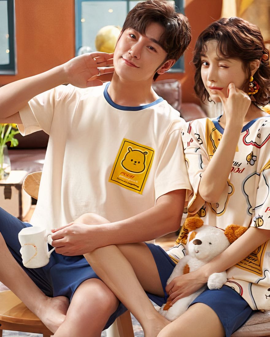 Two-piece cotton pajamas with bear pattern worn by a couple sitting on a chair in a house