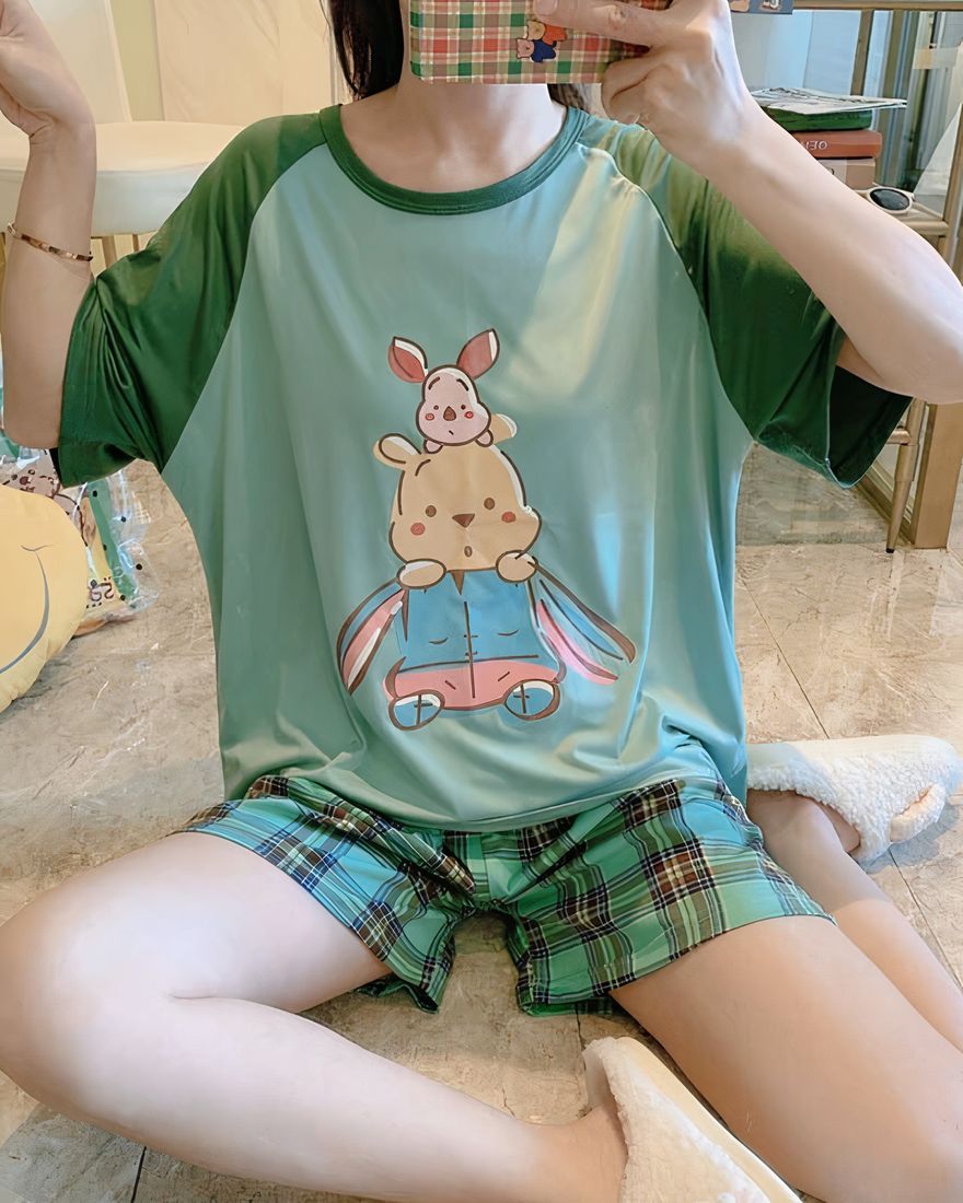 Two-piece pyjamas with a green Winnie and Piglet motif worn by a woman and a pair of shorts with a checkered pattern