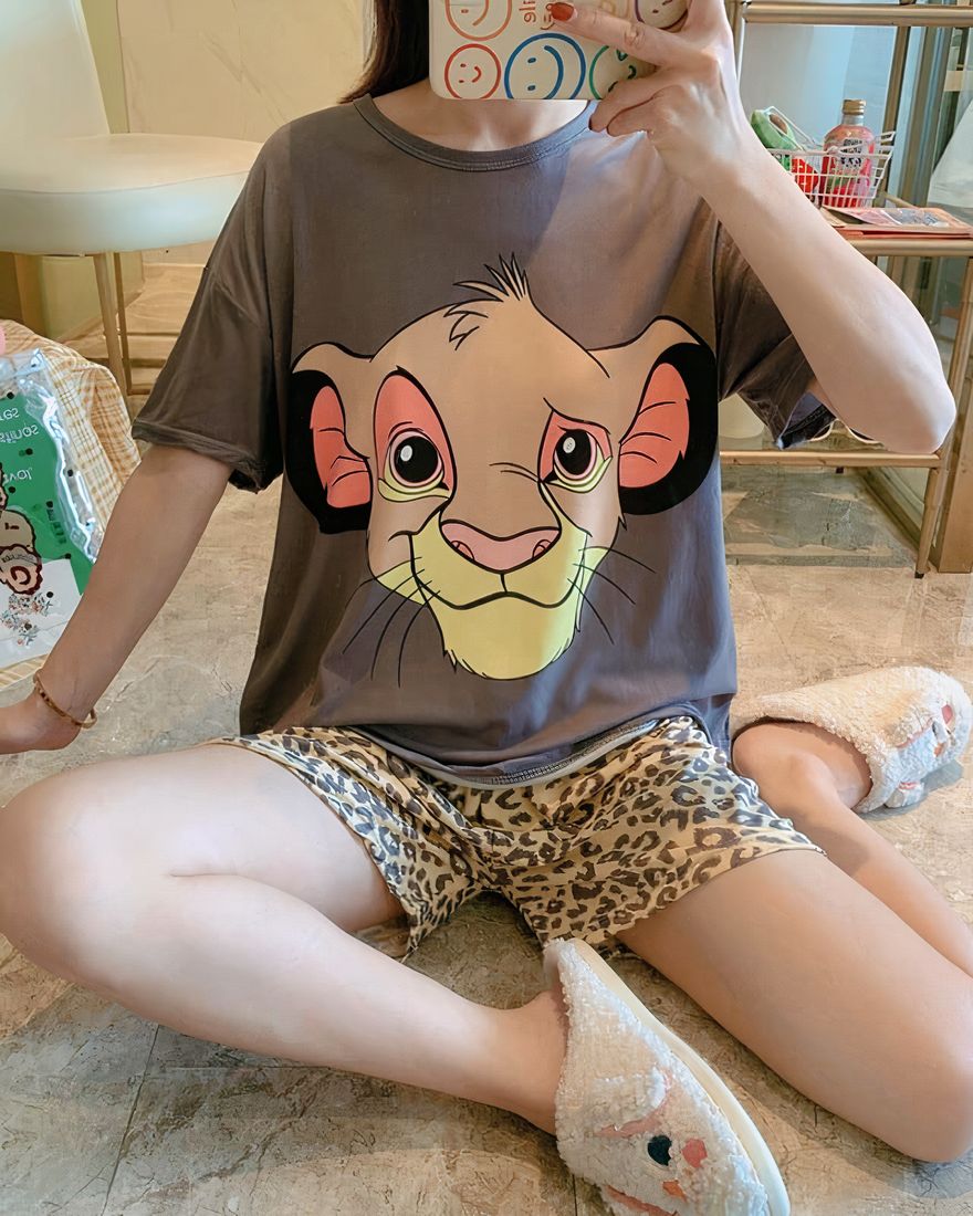 Brown two-piece pyjama set with Simba motif worn by a woman in a house