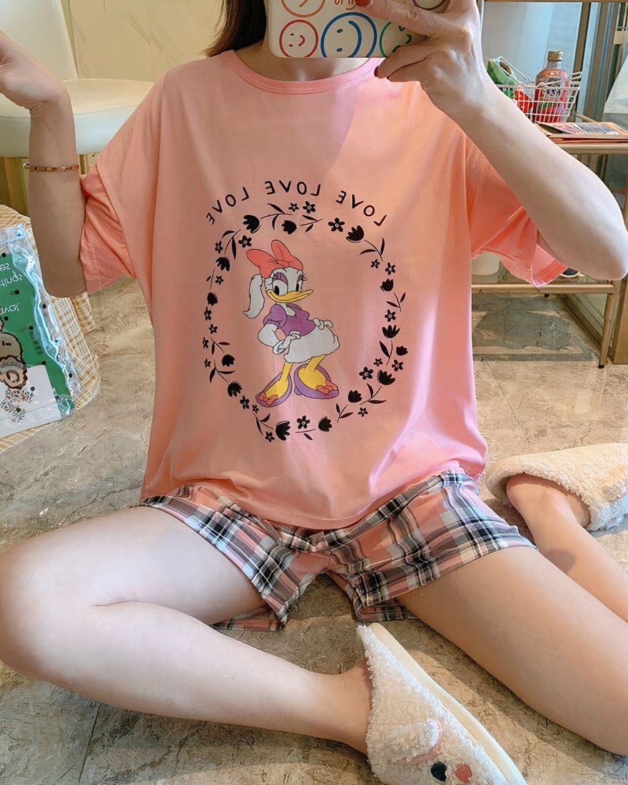 Two-piece pyjama t-shirt and shorts with Daisy pattern worn by a seated woman taking a picture