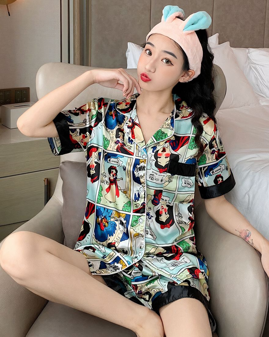 Two-piece pyjamas in satin with Snow White print worn by a woman wearing a rabbit bandana sitting on a chair in a house