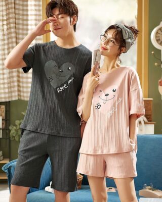 Pyjama t-shirt and plain cotton shorts with love me inscription worn by a fashionable couple in a house