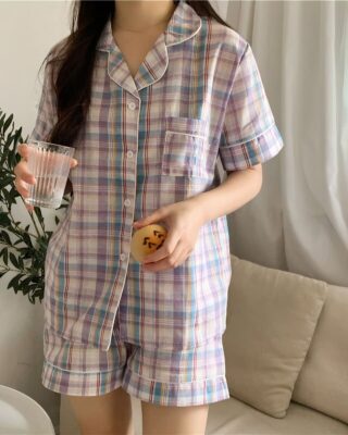 Short-sleeved pyjamas with folded collar for women worn by a woman in front of a sofa in a house