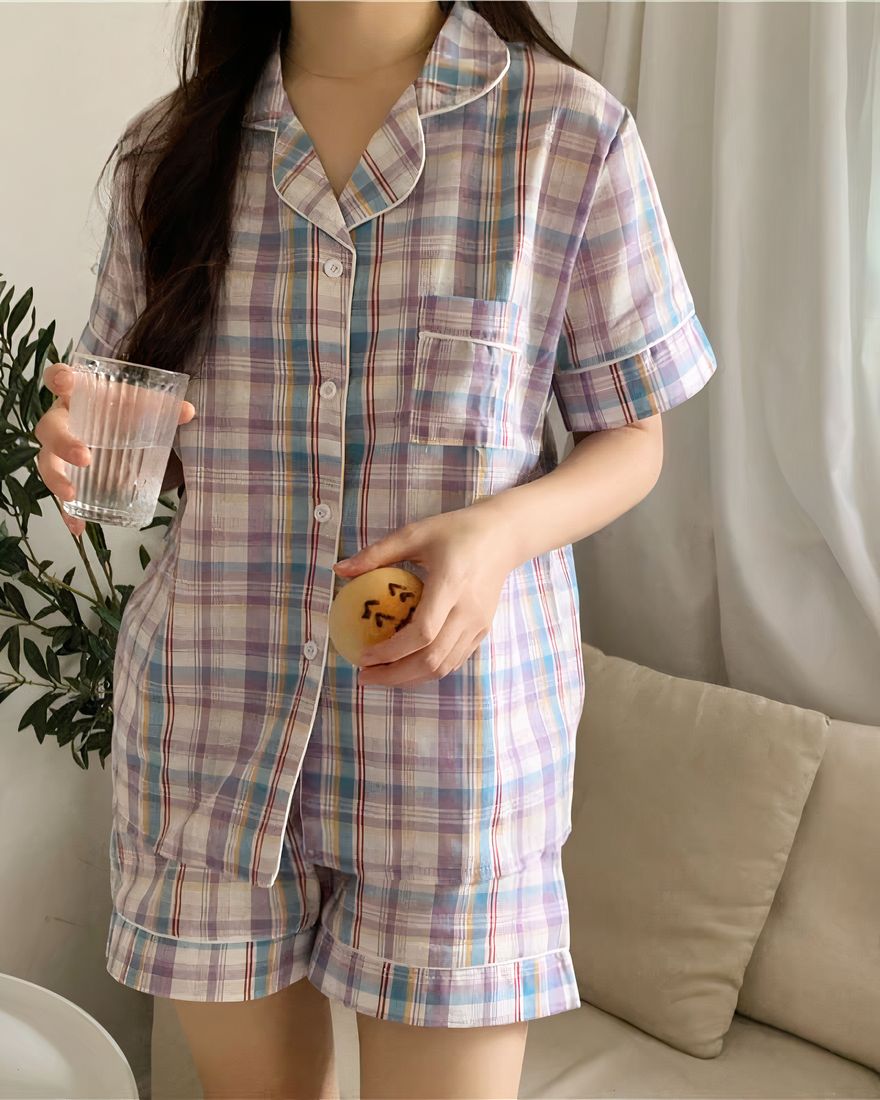 Short-sleeved pyjamas with folded collar for women worn by a woman in front of a sofa in a house