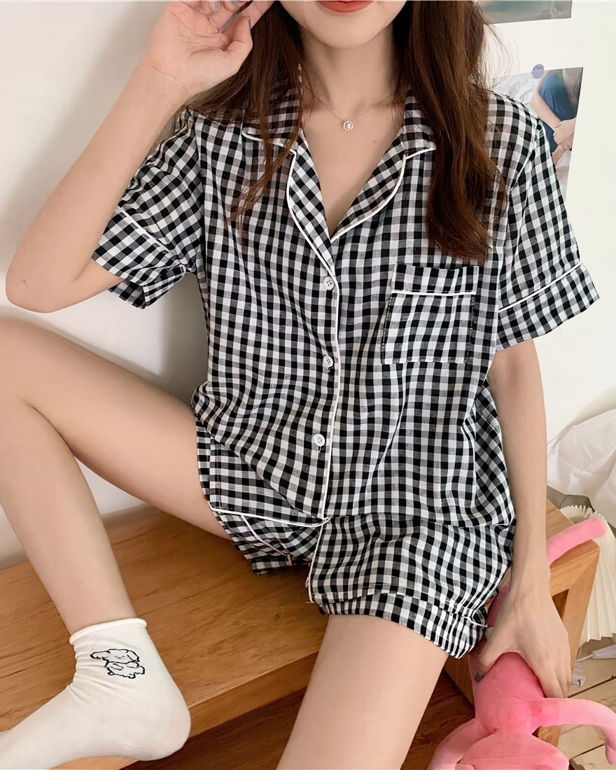 Fashionable black and white checkered short sleeve pajama set for women worn by a woman sitting on a table in a house