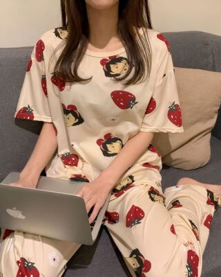 Two-piece short-sleeved pajamas for women worn by a woman sitting on a capanet in a house