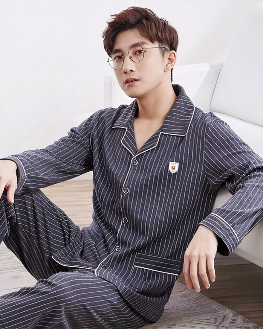 Striped pajamas for men worn by a man sitting on a carpet in a house