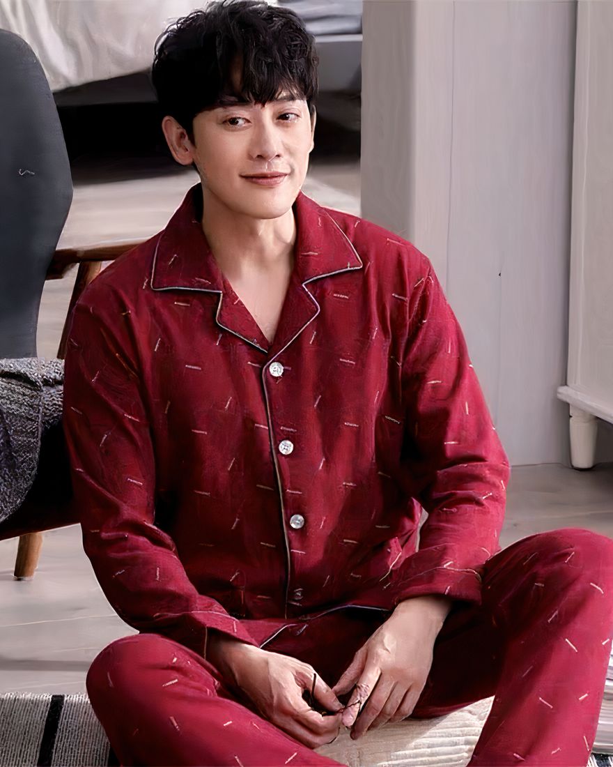 Classic men's pajamas worn by a man sitting on a carpet in front of a chair in a house
