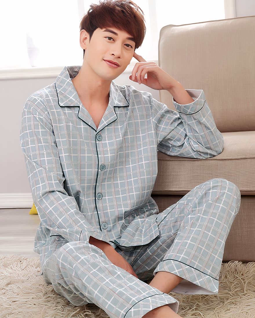 Men's pajamas with checks worn by a man sitting on a carpet in a house