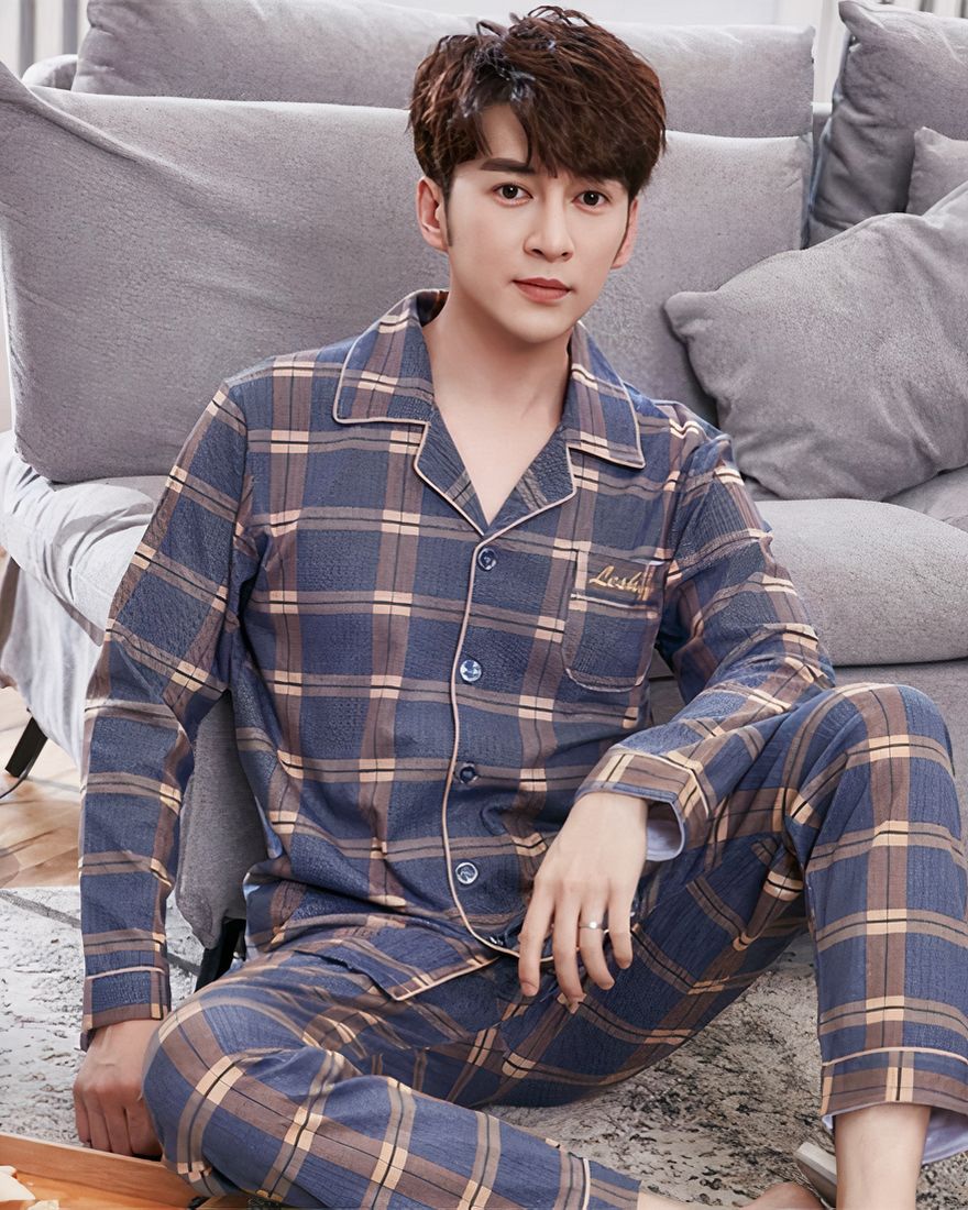 Men's double check pajamas worn by a man sitting on a carpet in front of a sofa in a house