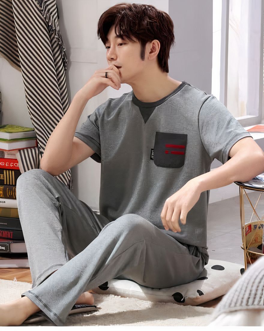 Short sleeved pajamas for men worn by a man who sits on a carpet in a house