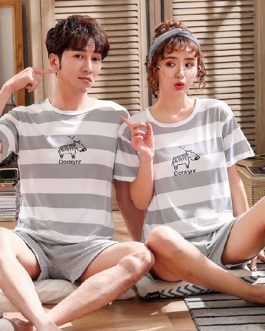 Lined pyjamas for couple with pattern worn by a couple sitting on a carpet in a house