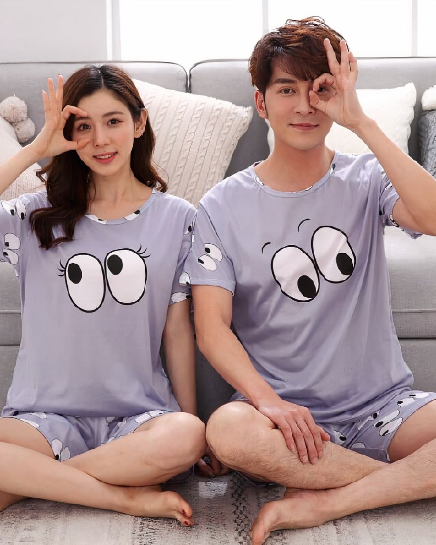 Pajama set with eye pattern for couple worn by a couple sitting on a carpet in a house