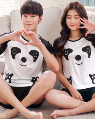 Pajamas for couple with panda pattern worn by a couple sitting on a carpet in front of a sofa in a house