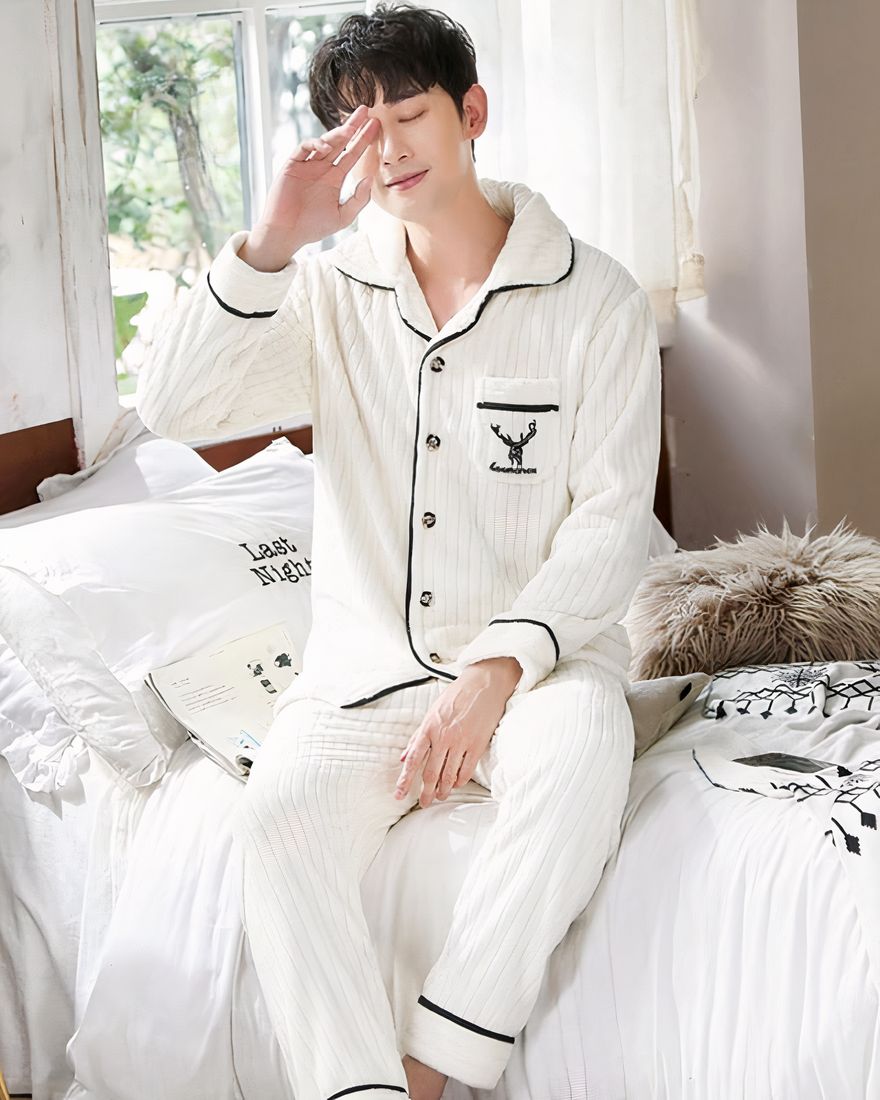 Polyester pajamas for men with a lined pattern worn by a man sitting on a bed in a house