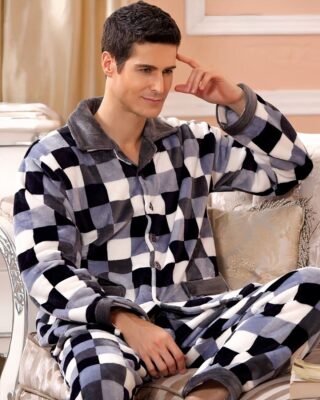 Men's checkered fleece pajamas worn by a man sitting on a sofa in a house