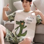 Short sleeve summer outfit with crocodile pattern worn by a man sitting on a carpet in a house