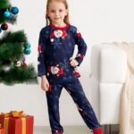 Snowflake and Santa printed pajamas for the family worn by a little girl in front of a Christmas tree in a house