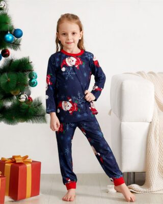 Snowflake and Santa printed pajamas for the family worn by a little girl in front of a Christmas tree in a house