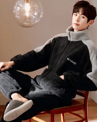 Black winter pajamas for men worn by a man sitting on a chair in a house