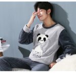 Pajamas with Panda pattern for men worn by a man sitting on a sofa in a house