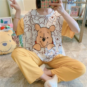 Yellow and white women's Winnie short sleeve pajamas worn by a seated woman taking a picture in front of a mirror