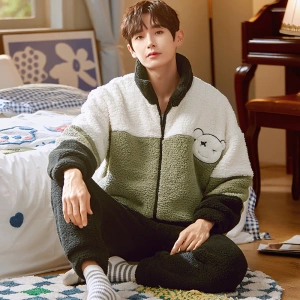 Winter warm pajamas with high collar worn by a man sitting on a carpet in front of a bed in a house