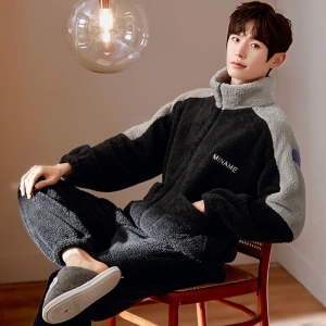 Black winter pajamas for men worn by a man sitting on a chair in a house