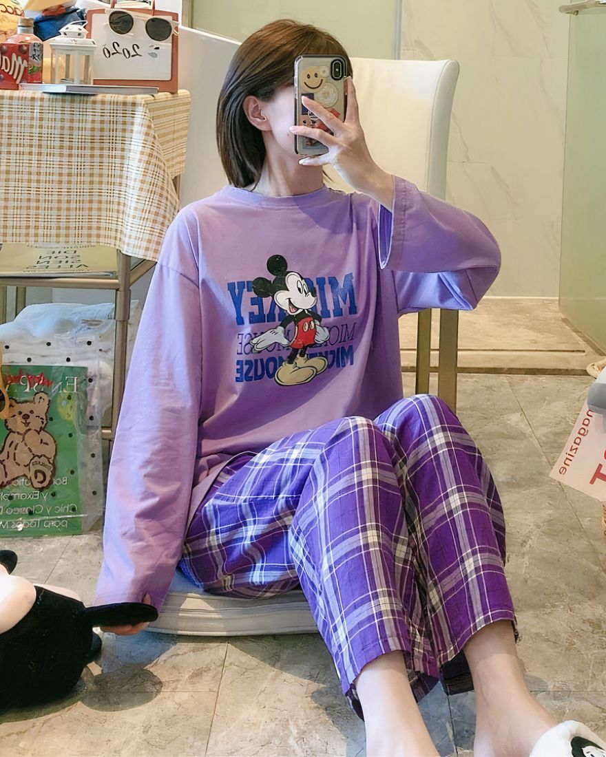Mickey pajamas with purple checkered pants worn by a woman taking a picture in a house
