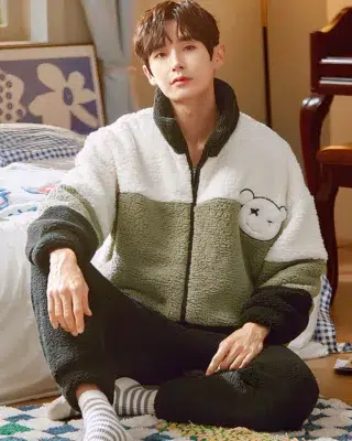 Winter warm pajamas with high collar worn by a man sitting on a carpet in front of a bed in a house