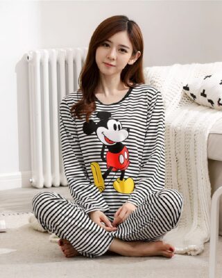 Mickey striped pajamas for women worn by a woman sitting in front of a bed in a house