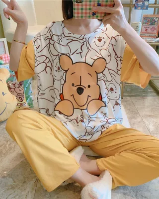 Yellow and white women's Winnie short sleeve pajamas worn by a seated woman taking a picture in front of a mirror