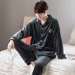 Plain fleece pajamas with collar for couple worn by a man sitting on a bed in a house
