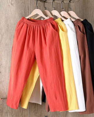 Several casual women's trousers made of cotton and linen in white, yellow, brown, black, and orange hang on hangers.