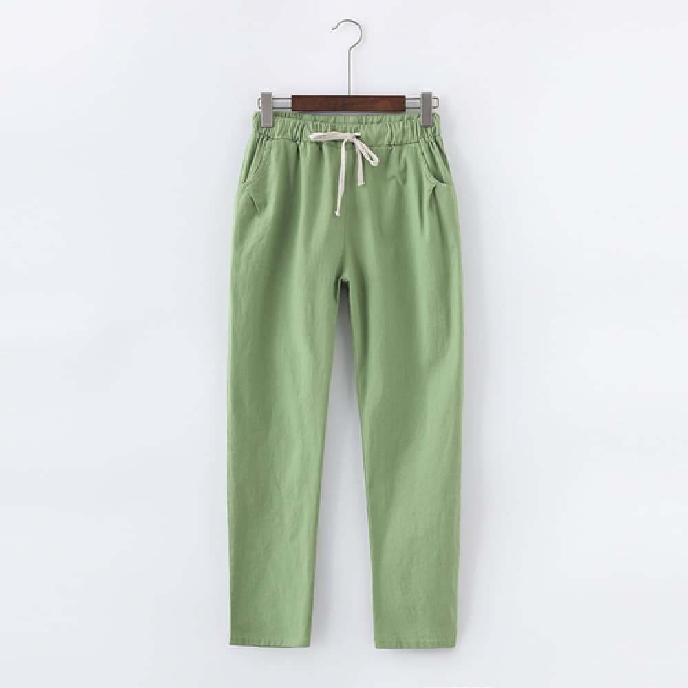 A pair of light green cotton and linen pants hanging on a hanger