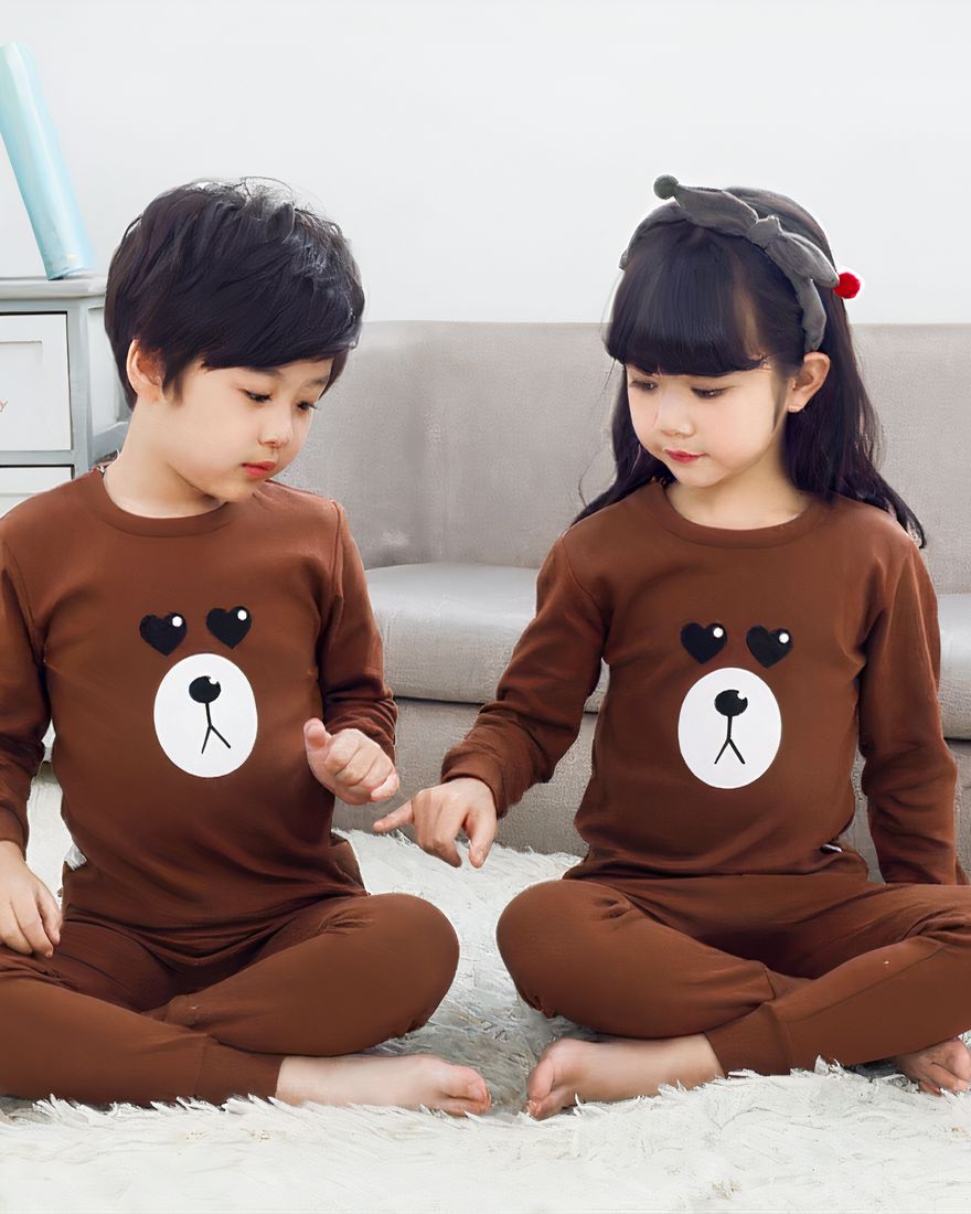 Brown spring pajamas with bear pattern for children with two children wearing the pajamas and a background a sofa