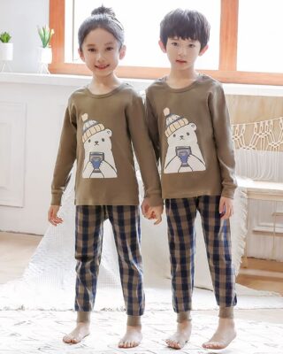 Spring pajamas with beige sweater and plaid pants for children with two children wearing the pajamas is a background a room