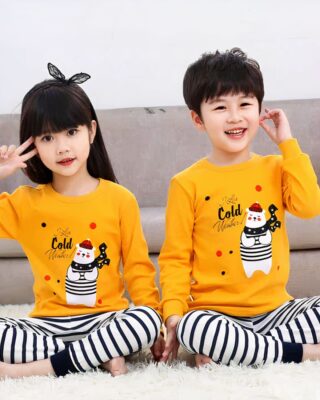 Spring pajamas with yellow sweater and black striped white pants with two children wearing the pajamas and a background a sofa