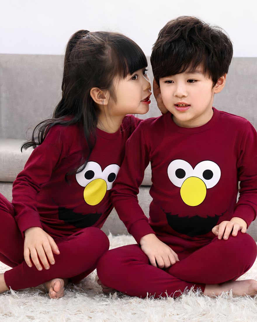 Two-piece burgundy spring pajamas for children with two children wearing the pajamas and a background sofa