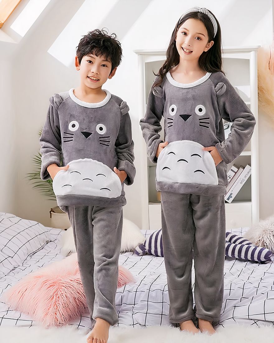 Grey fleece pajamas with Toroto print for a little boy and a little girl wearing a headband on a bed in a house
