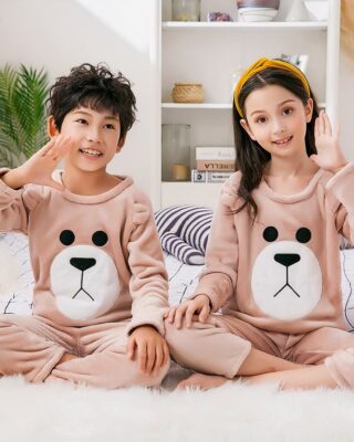 Brown fleece pajamas for children worn by a little girl and a little boy sitting on a carpet in a house