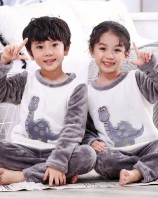 Two-piece grey flannel pajamas with dinosaur design for children worn by a little boy and a little girl in a house