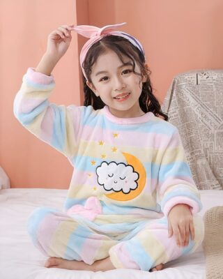 Rainbow colored fleece pajamas for children worn by a little girl on a bed in a house